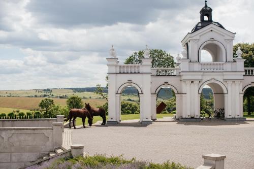 a horse standing in front of a white building at Edem Resort Medical & SPA in Strelki