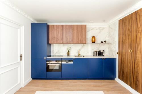 a blue kitchen with white walls and wooden cabinets at Luxury 3 Bedroom & 3 Bathroom Apartment - Marais in Paris