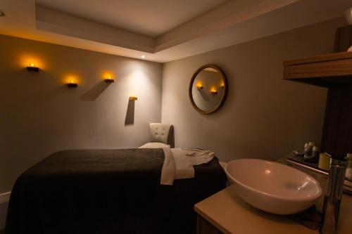 a bathroom with a sink and a bed and a mirror at Harbour Hotel & Spa Chichester in Chichester
