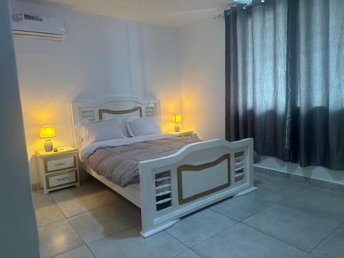 a bedroom with a white bed with two night stands and two lamps at Villa bord de mer louis in Libreville