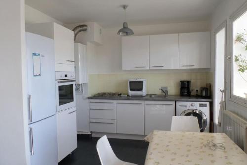 une cuisine avec des armoires blanches et une table avec des chaises dans l'établissement T3 Tout confort-20 min à pied plage, à Fréjus