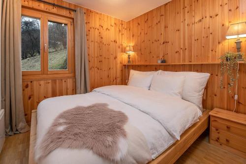 Grand Chalet Veysonnaz w/Spa في سيون: غرفة نوم بسرير وبطانية بيضاء ونافذة