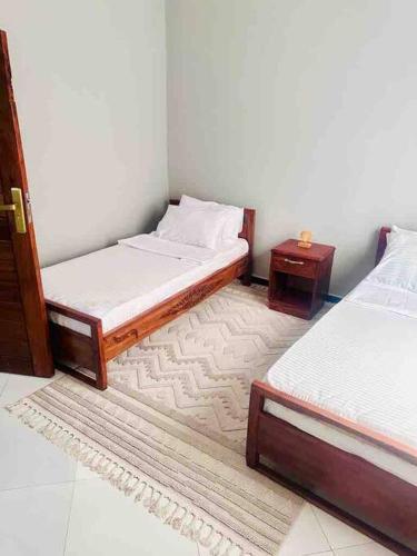 Habitación con 2 camas individuales y mesa. en kaya homes en Dar es Salaam