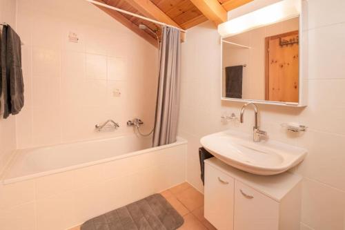 Grand Chalet Veysonnaz w/Spa في سيون: حمام أبيض مع حوض وحوض استحمام