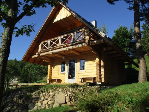 a log cabin with a porch and a balcony at Ezerkalni in Raiskums