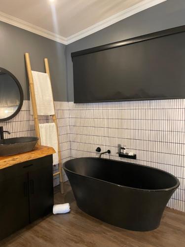 a black bath tub in a bathroom with a tv at Mont d'Or Monte Bello Estate in Bloemfontein