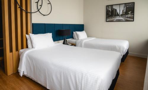 two beds in a room with white sheets at eSuítes Congonhas by Atlantica in Sao Paulo