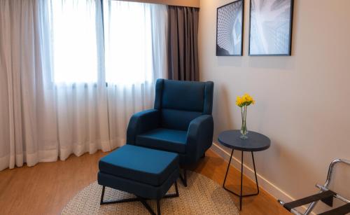 a room with a blue chair and a table at eSuítes Congonhas by Atlantica in Sao Paulo
