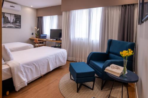 a hotel room with a bed and a blue chair at eSuítes Congonhas by Atlantica in Sao Paulo