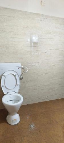 a white toilet in a room with a wall at Prakruthi home 2 in Mangalore