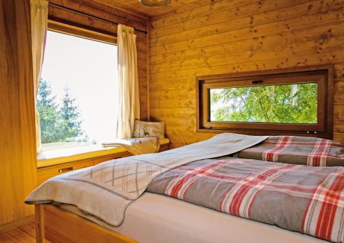 a log cabin bedroom with a bed and a window at Almliesl STEF-633 in Sankt Stefan im Lavanttal