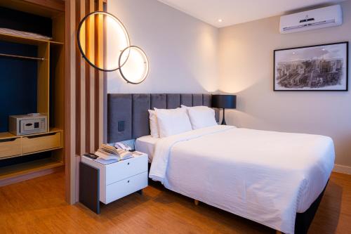 a bedroom with a large white bed and a night stand at eSuítes Congonhas by Atlantica in Sao Paulo
