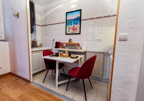 une petite cuisine avec une table et des chaises rouges dans l'établissement Le Nid Douill'Aix Netflix Wifi Centre-ville, à Aix-les-Bains