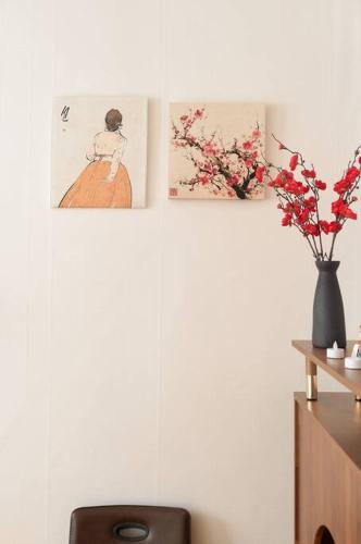 zwei Bilder und eine Vase mit Blumen an einer Wand in der Unterkunft LAON Stay in Seoul