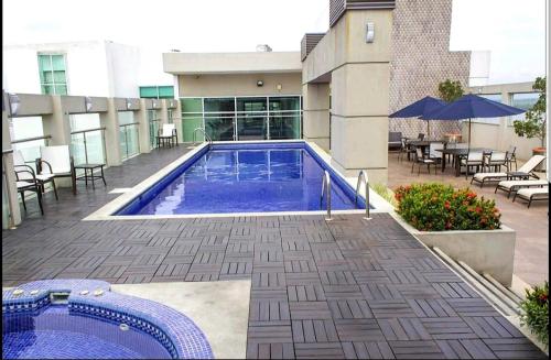 una piscina con tavoli e sedie e un edificio di Ecusuites Family Depto Resort Riverfront Gye a Guayaquil