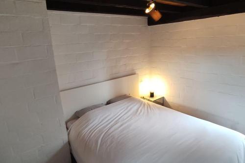 a white bed in a room with a light on it at Havane13 in Hastière-par-delà