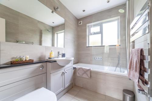 a bathroom with a tub and a sink and a shower at Garden Flat short walk to Kingston & Richmond Park in Strawberry Hill