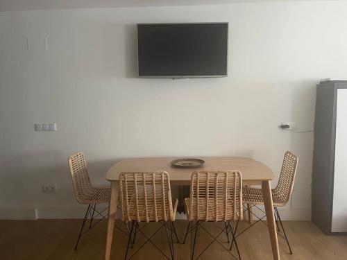 a table with chairs and a television on a wall at Apartamento Loft centro Santiago in Santiago de Compostela