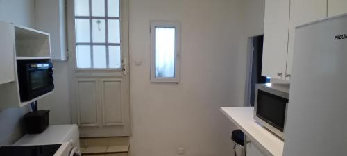 une cuisine blanche avec une porte et une télévision dans l'établissement Appartement calme aux abords de Paris, Seine, à Boulogne-Billancourt