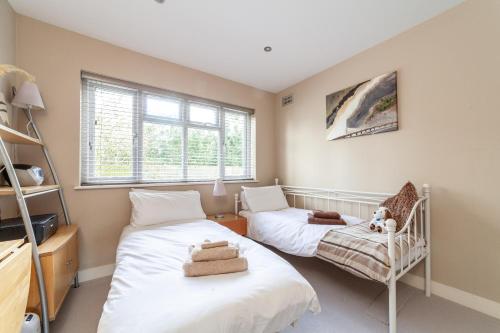 two beds in a room with two windows at Garden Flat short walk to Kingston & Richmond Park in Strawberry Hill