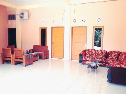 a living room with couches and chairs and tables at Wisma Dhana Syariah in Praya