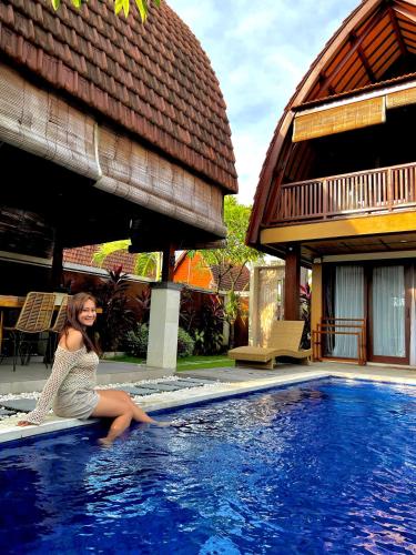a woman sitting on the edge of a swimming pool at Bhumi Lovina Residence & Villa in Singaraja