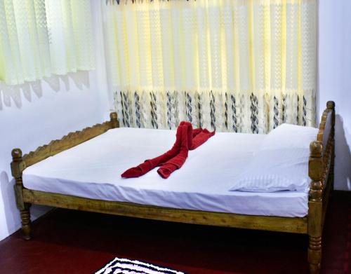uma cama com uma meia vermelha em cima em Sinharaja Pitadeniya Hut em Deniyaya