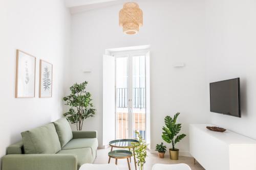 a living room with a couch and a tv at Villalobos Suites by Luxury Suites Cadíz in Cádiz