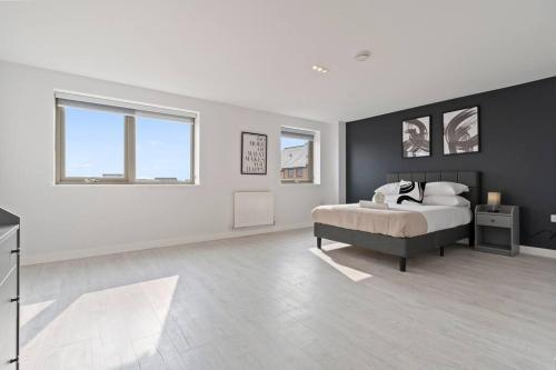 a white bedroom with a bed and two windows at Exquisite 7 Bedroom 5.5 Bathroom House - Over 1900 sqft - Close to City Centre with Free Parking, Fast W-Fi and SmartTVs by Yoko Property in Northampton