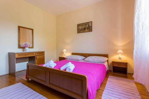 a bedroom with a large bed with a pink blanket at Peaceful Oasis in Banići