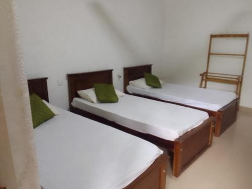 a room with three beds with green pillows at Sisila Guest House in Polonnaruwa