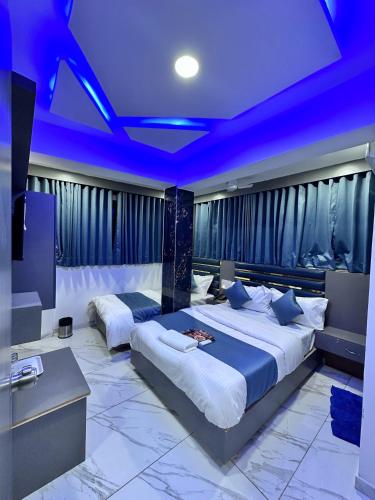 a bedroom with two beds and a blue ceiling at Hotel The Pacific in Ahmedabad