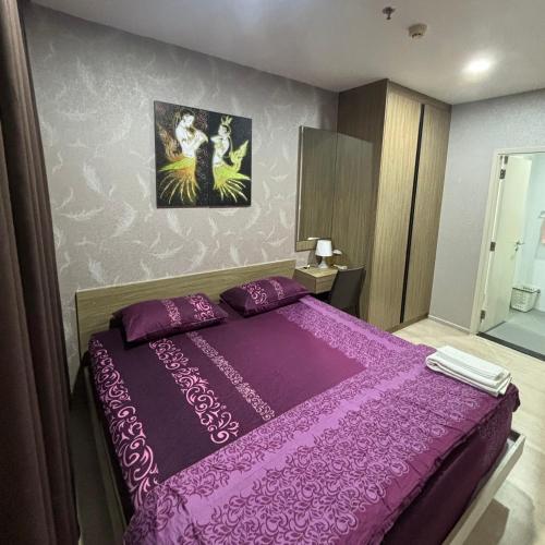 een slaapkamer met een paars bed met een paarse sprei bij The Gallery in Samut Prakan
