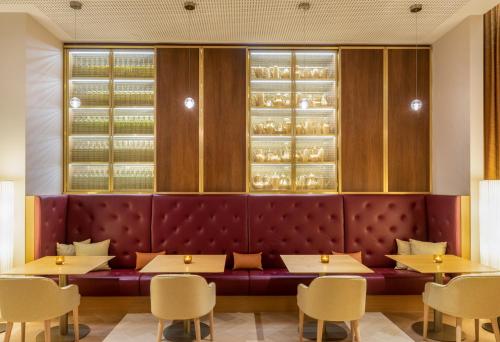 a restaurant with a red bench and tables and chairs at Mövenpick Hotel Stuttgart Messe & Congress in Stuttgart
