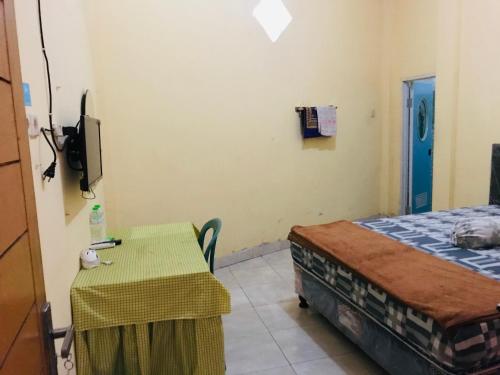 a room with a table and a bed and a small table and chair at Wisma Dhana Syariah in Praya