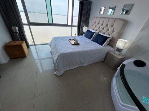 a bedroom with a large bed and a bath tub at Ecusuites Riverfront One Vista al Río Jacuzzi Hidro in Guayaquil