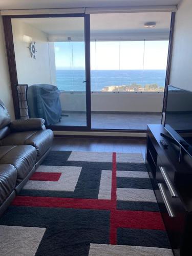 a living room with a couch and a view of the ocean at Departamentos Mednav Montemar & Spa in Concón