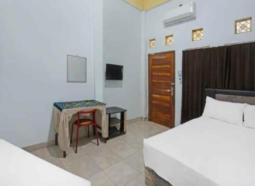 een slaapkamer met een bed, een tafel en een bureau bij Wisma Dhana Syariah in Praya