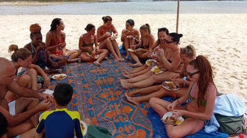 a group of people sitting on the beach eating food at Sweet Home in Kiwengwa