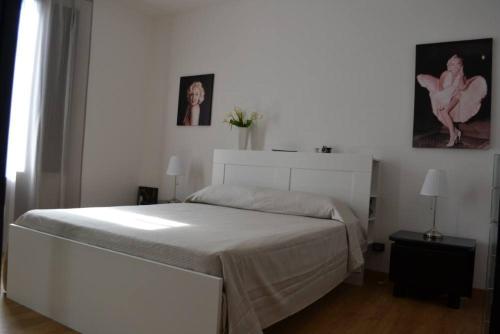 パレルモにあるCasa Colorataの白いベッドと2枚の写真が備わる白いベッドルームです。