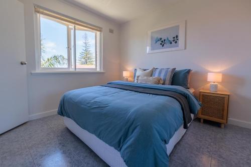 a bedroom with a bed with a blue blanket and a window at Stunning Apartment In South Perth in Perth