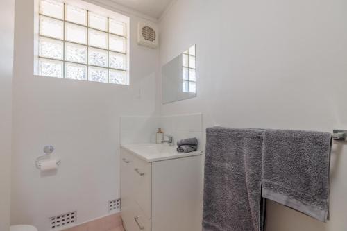 a white bathroom with a sink and a window at Stunning Apartment In South Perth in Perth