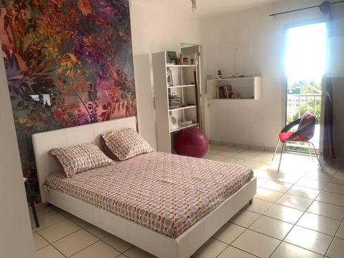 1 dormitorio con 1 cama y una pintura en la pared en Appartement spacieux, en Sainte-Clotilde