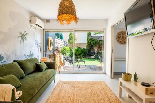 - un salon avec un canapé vert et une télévision dans l'établissement Cozy 1-Br Apartment heart of Palm Beach district, à Cannes