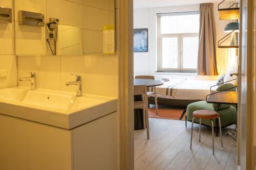 Smartflats - L'Orangerie I Maastricht في ماستريخت: حمام مع حوض وغرفة مع سرير