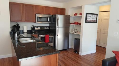 a kitchen with stainless steel appliances and wooden cabinets at Modern and Pristine Condo -By the GT Commons in Traverse City