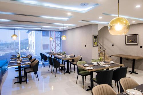 a restaurant with tables and chairs and a large window at BON Hotel Nest Garki II Abuja in Abuja