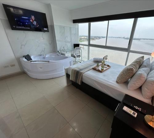 een grote badkamer met een bad en een tv bij Ecusuites Studio Two Riverfront con Jacuzzi Hidro Privado in Guayaquil