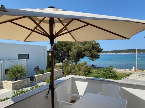 einen Regenschirm auf einem Balkon mit Meerblick in der Unterkunft Apartments and Rooms Villa Luci in Barbat na Rabu