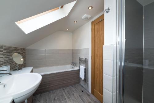 een badkamer met een wastafel en een bad bij Piggery Cottage in Llanasa